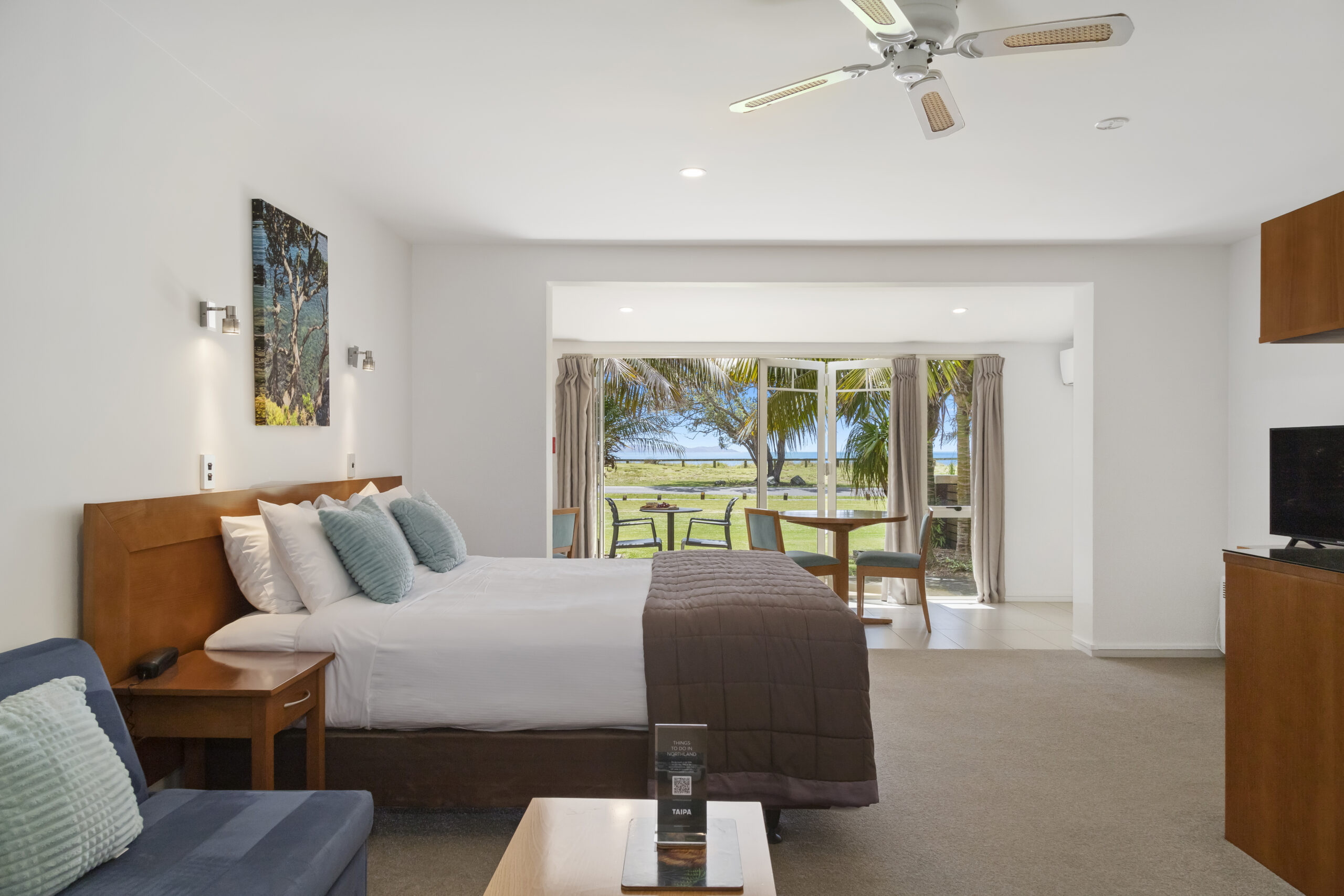 Modern resort room with ocean view and patio access through large windows.