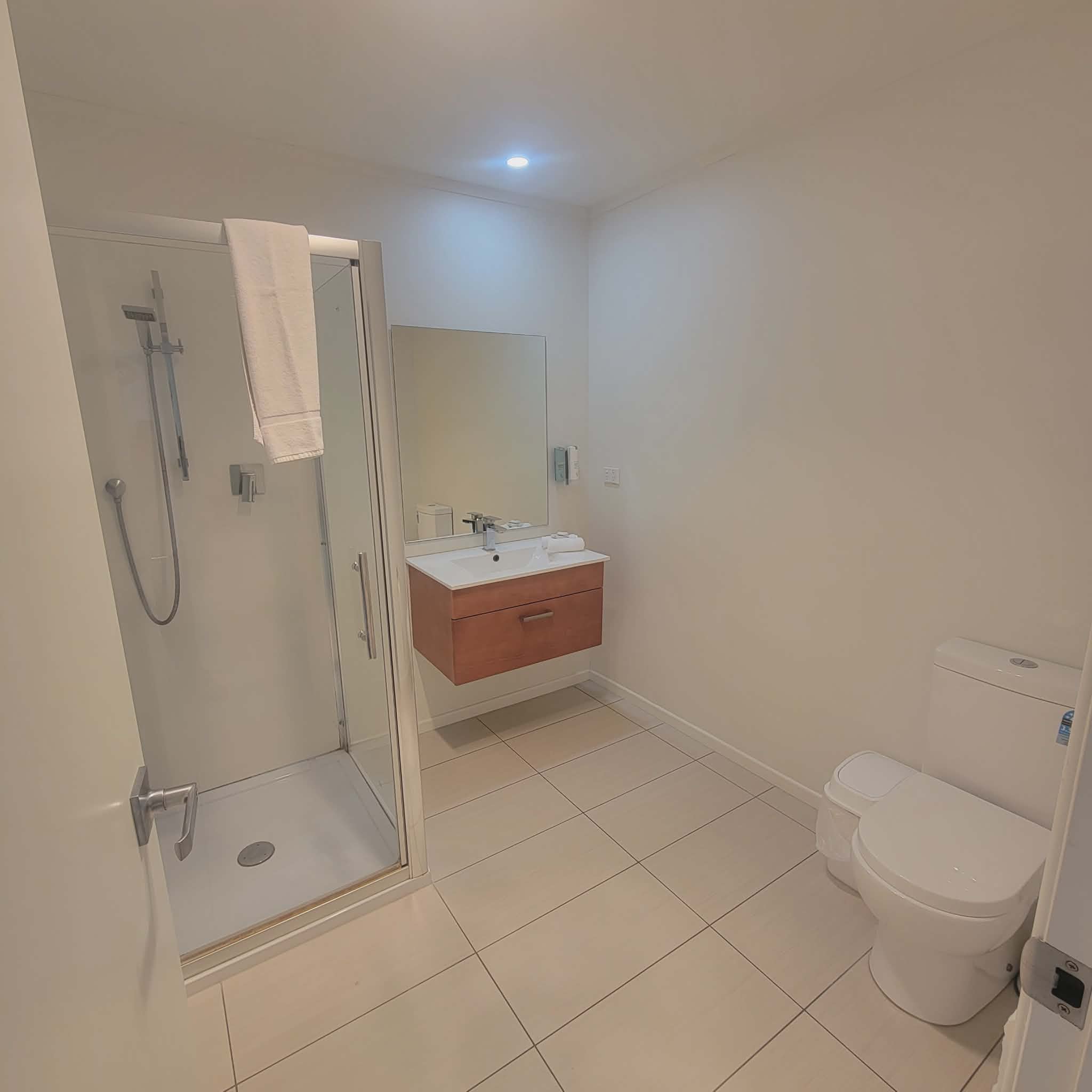 Modern bathroom at Taipa Beach Resort with walk-in shower, vanity, and tiled flooring.