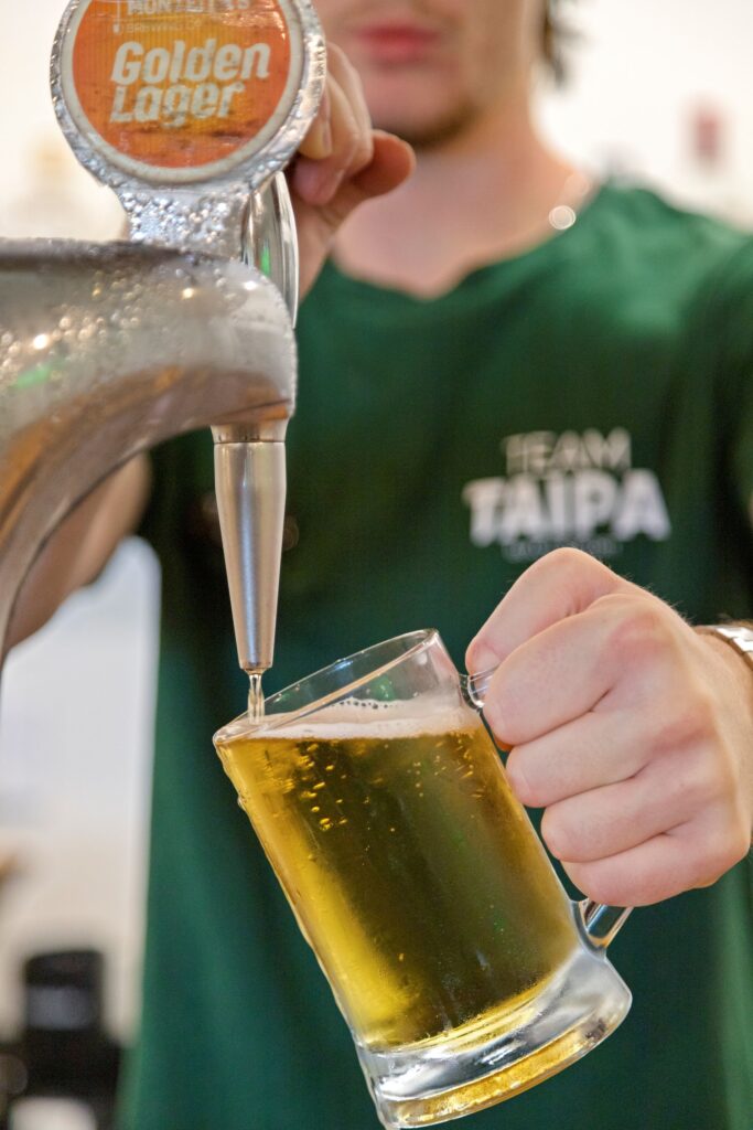 A cold tap beer being poured at Taipa Beach Resort Restaurant in Doubtless Bay, Northland, perfect for enjoying with a meal overlooking the beach.