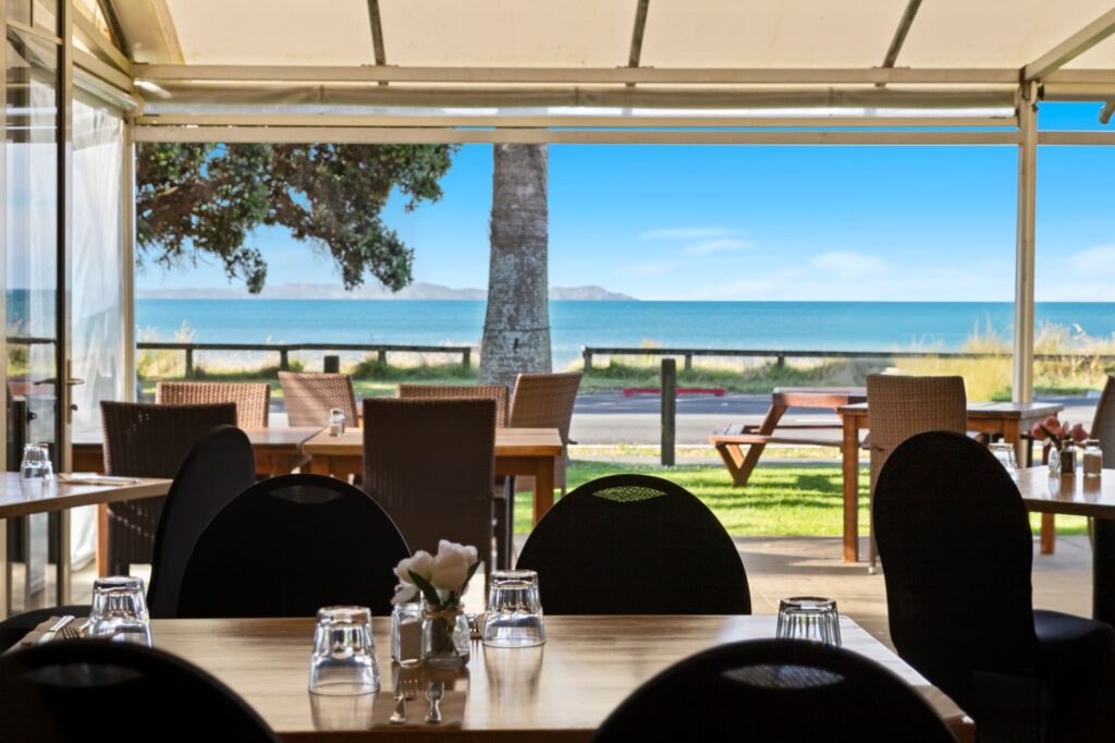 Restaurant seating with beachfront views at Taipa Beach Resort in Doubtless Bay, Northland, offering relaxed indoor and outdoor dining overlooking the ocean.